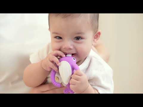 Baby happily chewing on a purple Narwhal teether, promoting teething relief and sensory play during bath time.