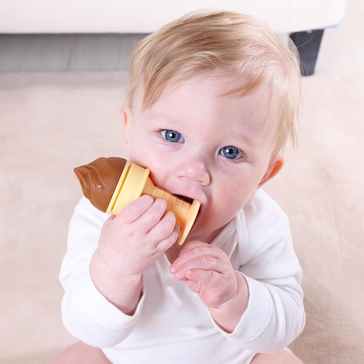 Blue-eyed baby chewing the chocolate brown scoop of Smily Mia ice cream teether close-up showing how the soft silicone scoop provides targeted front gum relief for teething babies