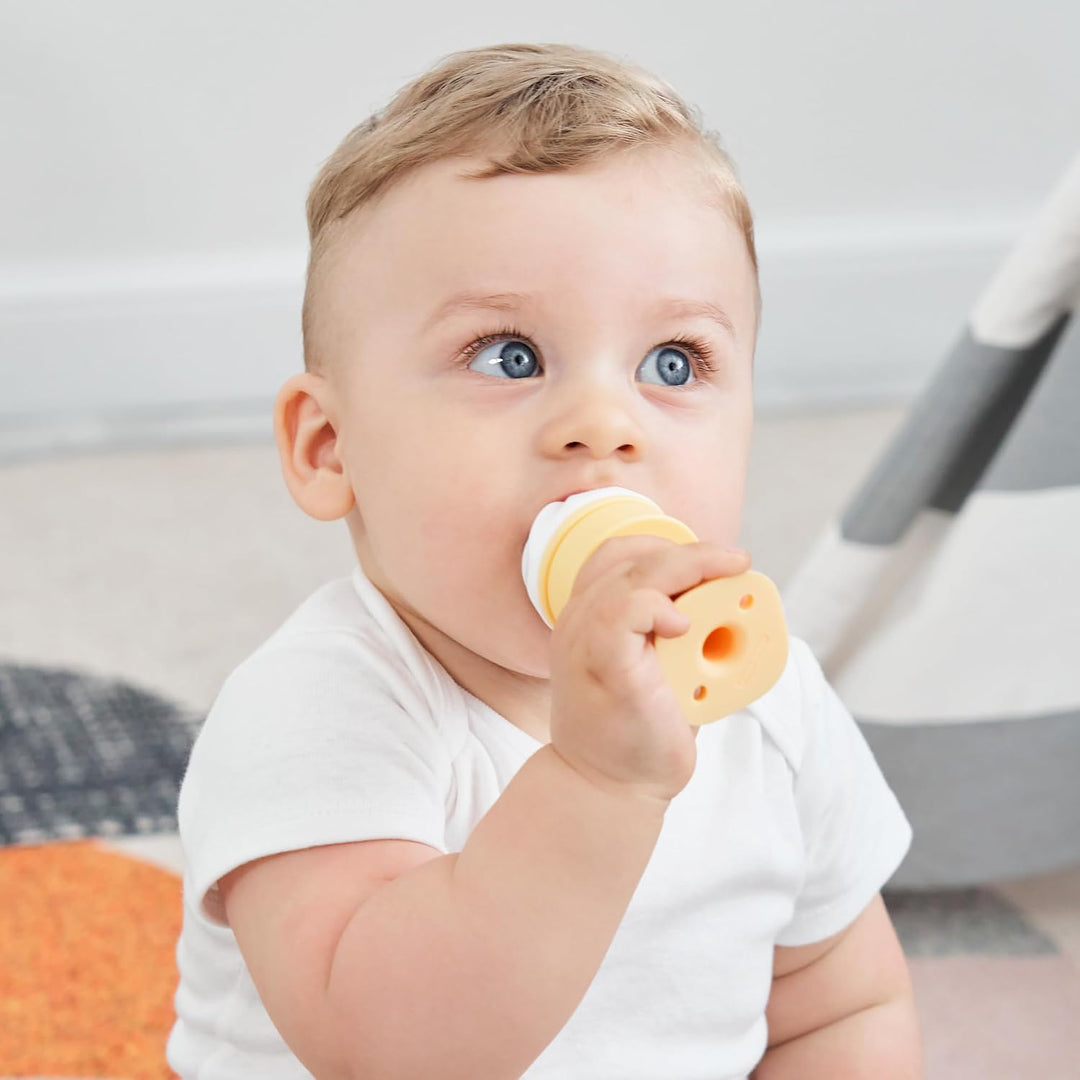 Close-up of blue-eyed baby chewing the textured cone section of Smily Mia ice cream teether showing how baby independently holds and mouths teether for gum relief