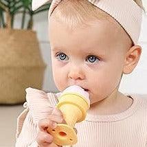 Baby girl in beige outfit and headband chewing Smily Mia yellow ice cream silicone teether