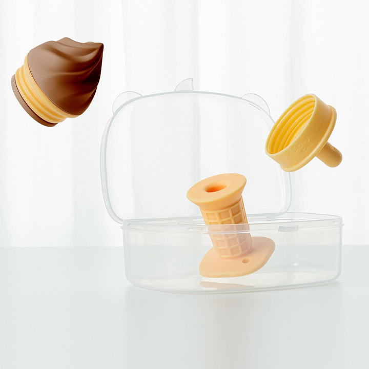Smily Mia ice cream teether parts floating above clear bear-shaped storage case showing chocolate scoop, yellow cone handle with base, and sealer cap — complete hygienic storage solution