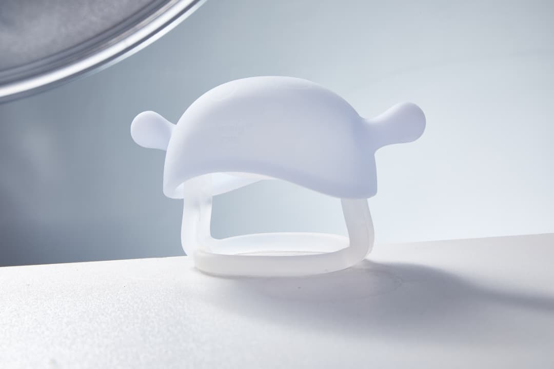 Smily Mia Little Mushroom Teething Mitten in crystal white color displayed on clean white surface showing full mushroom cap shape with smooth matte silicone texture and wrist ring