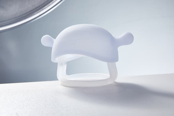 Smily Mia Little Mushroom Teething Mitten in crystal white color displayed on clean white surface showing full mushroom cap shape with smooth matte silicone texture and wrist ring