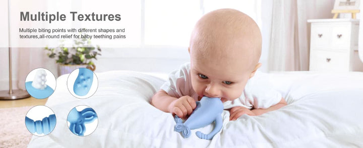  Baby lying on tummy chewing Smily Mia blue narwhal silicone teether showing multiple biting textures for all-round gum relief